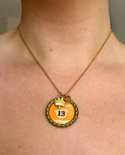 Necklace with a pendant featuring the number 13 on a person's neck.