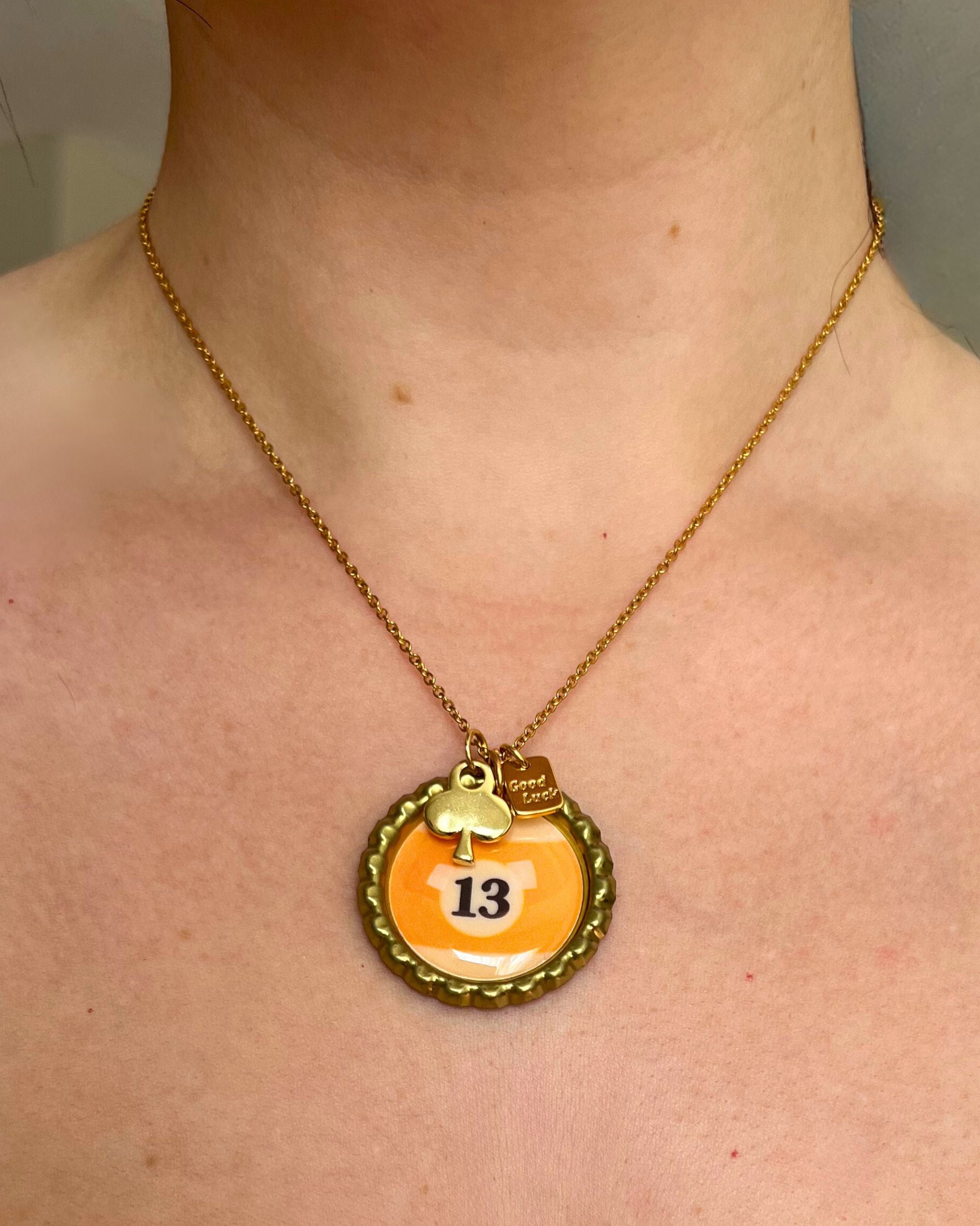 Necklace with a pendant featuring the number 13 on a person's neck.