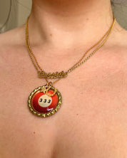 Necklace with a red and gold pendant worn by a person