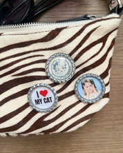 Zebra-patterned pouch with bottle cap charms on a wooden surface