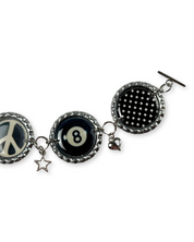Bracelet with various charms including a peace symbol, number 8, polka dot design, and heart on a white background.