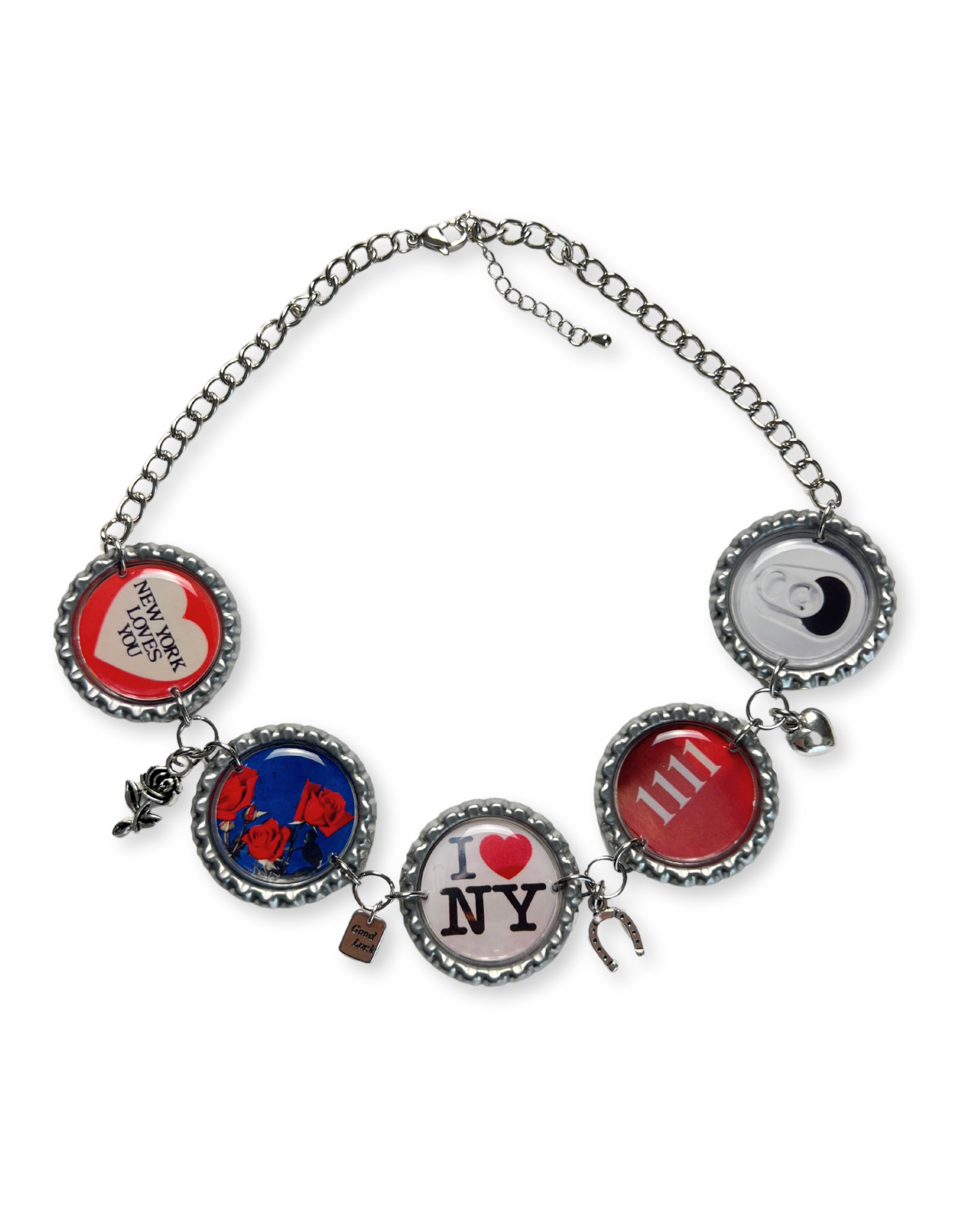 A handmade chain necklace with repurposed aluminum bottle caps featuring various designs including ones with a heart and 'NY' initials, and silver charms on a 925 sterling silver curb chain with a lobster clasp closure.