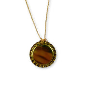 Gold necklace with a round pendant on a white background