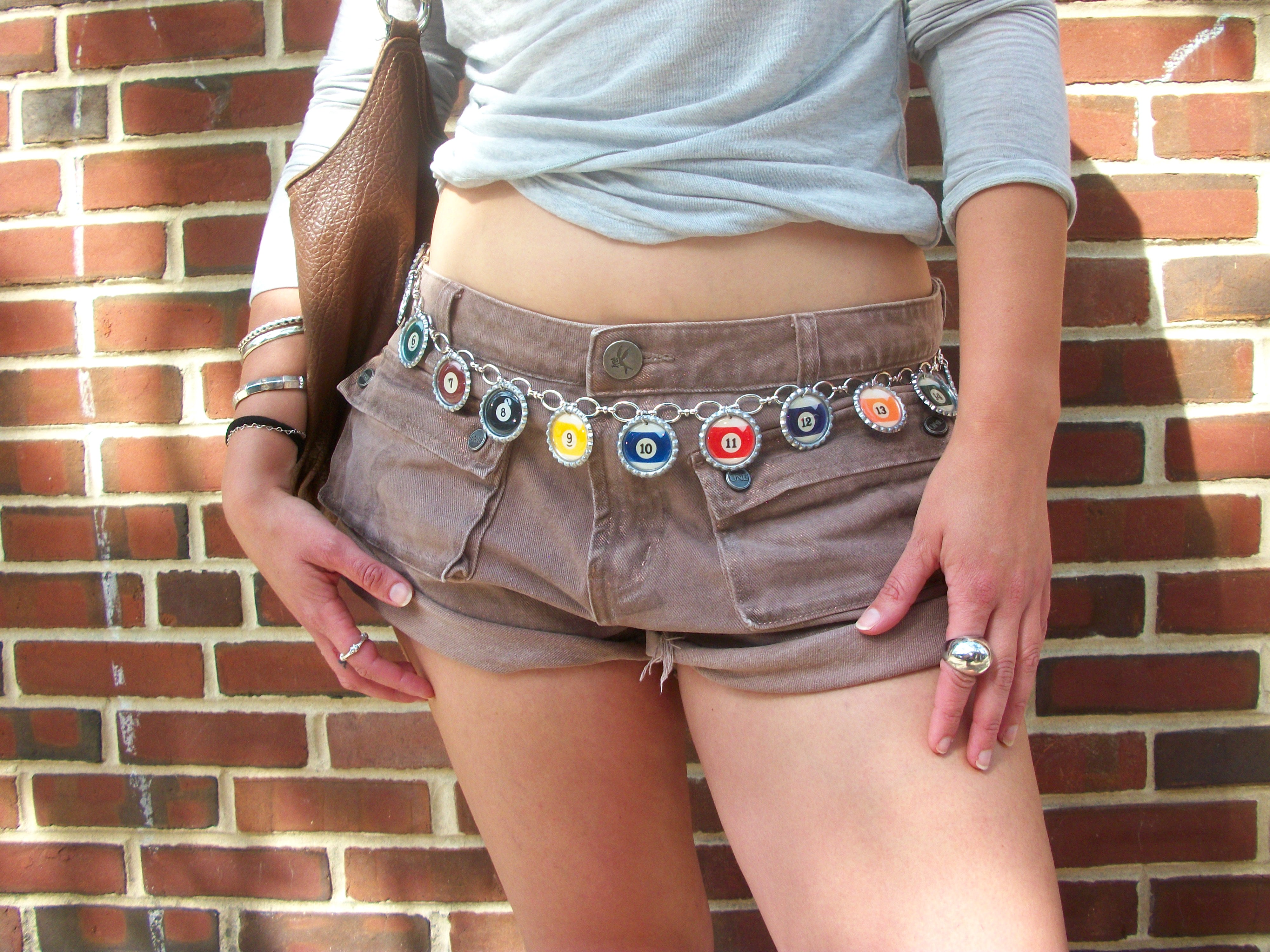 Person wearing brown shorts with colorful embellishments against a brick wall.