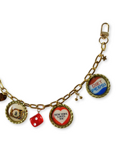 Gold charm bracelet with various charms including a Diet Pepsi bottle cap, a red die, and a New York Loves Me charm.