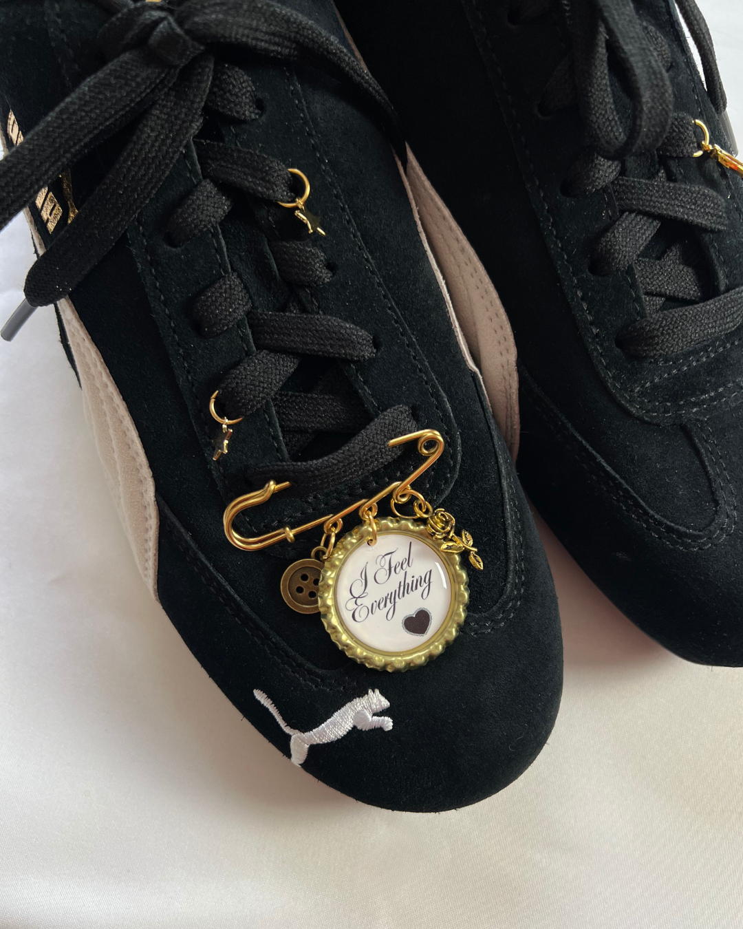 Black sneakers with gold charms on a white background