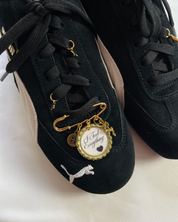 Black sneakers with gold charms on a white background