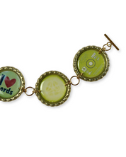 Bracelet with green bottle cap charms on a white background