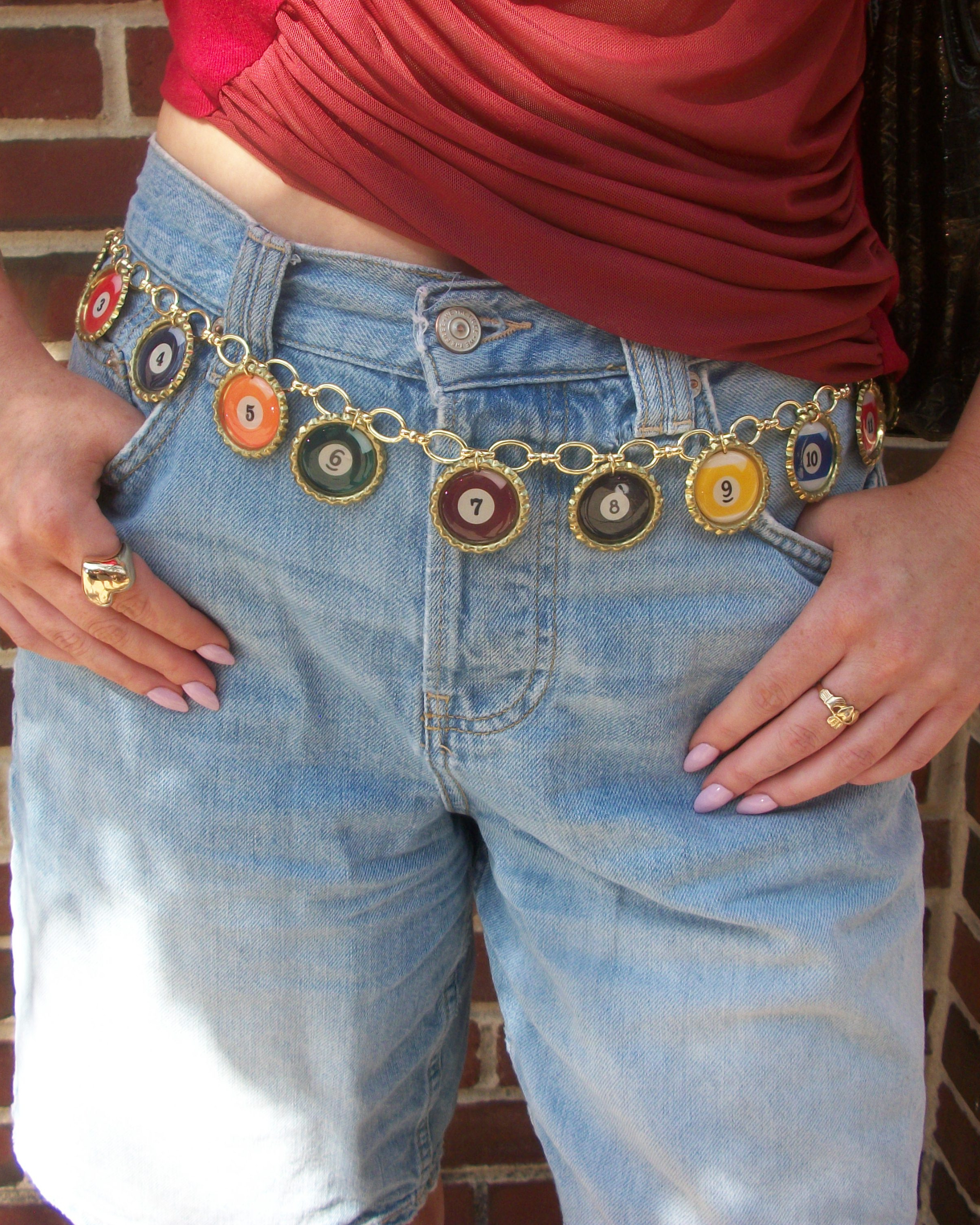 Person wearing a colorful belt with a red top and blue jeans.