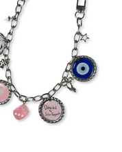 bag chain with various charms including a blue evil eye, pink dice, and round charm with text on a white background.