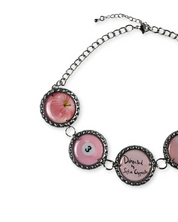Necklace with pink apple and eye design on a white background