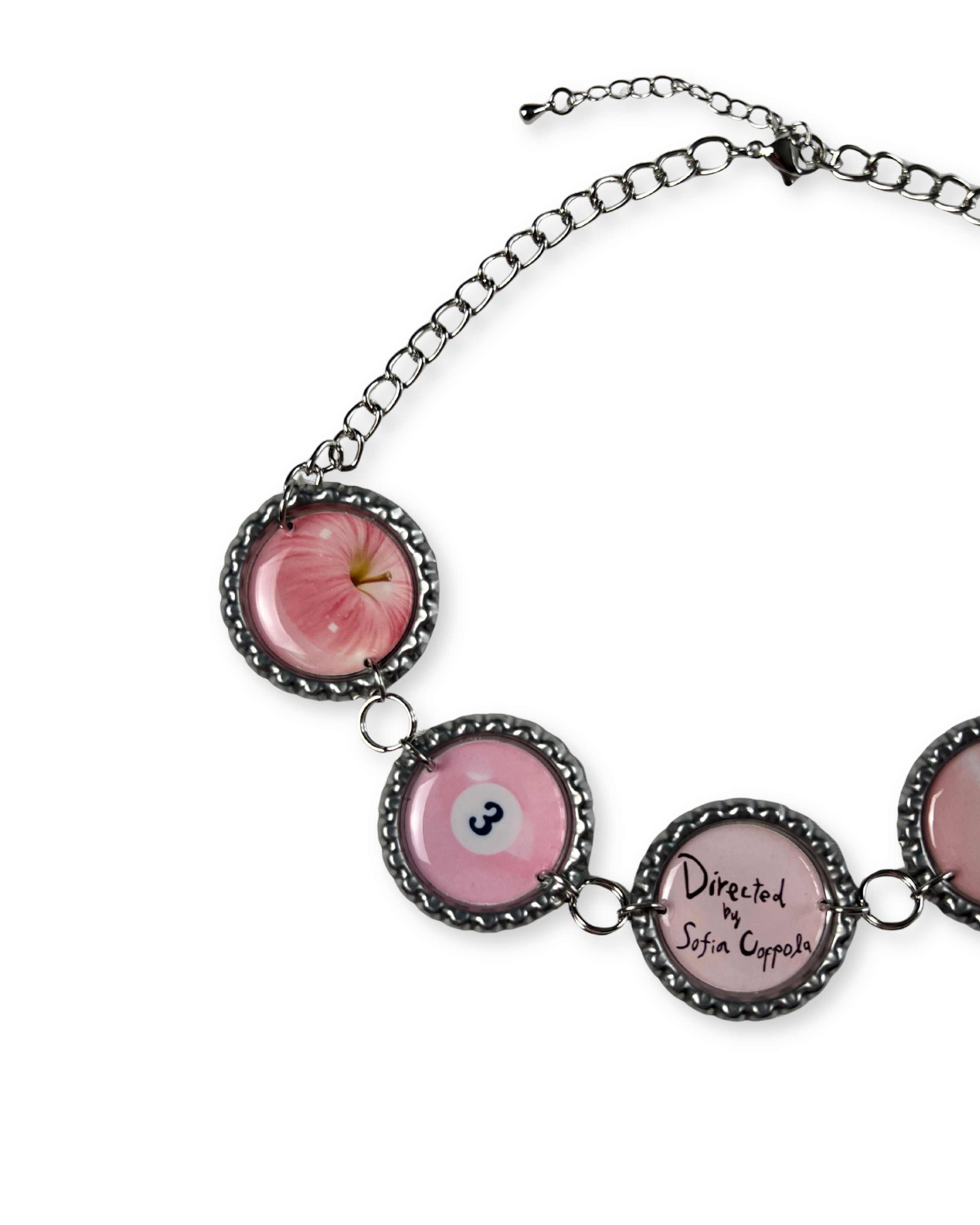 Necklace with pink apple and eye design on a white background